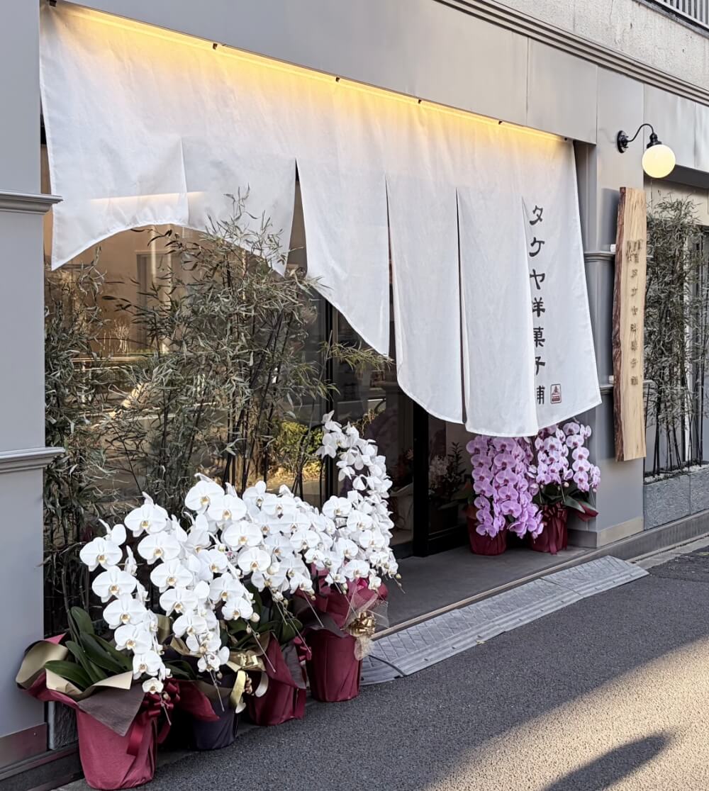 白いのれんと木の看板のある店先