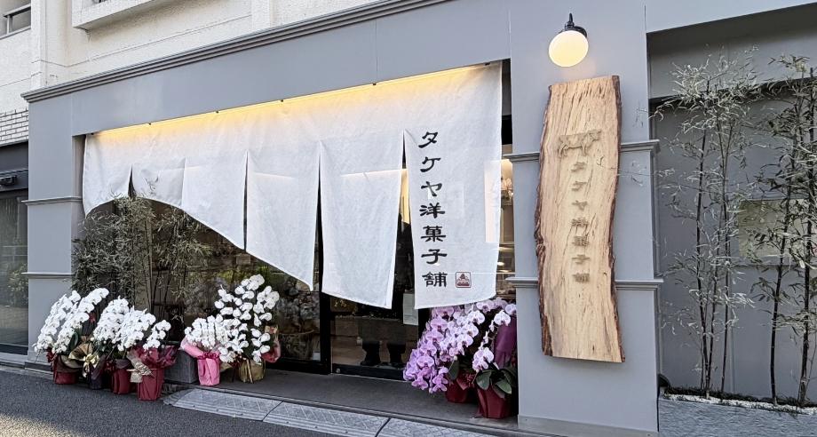 白いのれんと木の看板のある店先