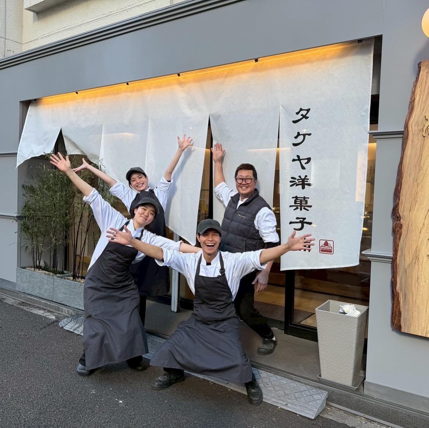 のれんの前で手を広げるスタッフ